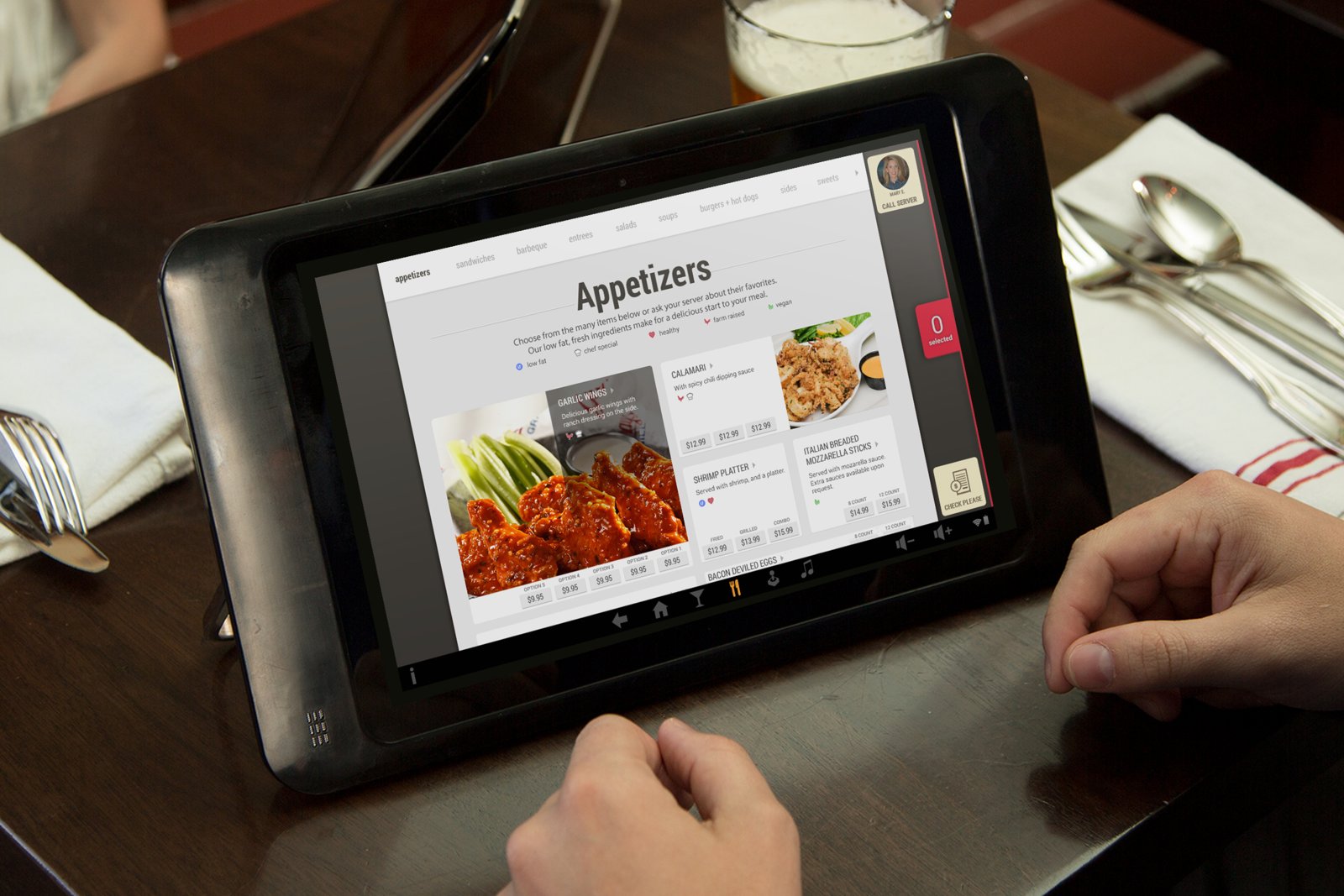 A Tanjarine tablet propped on a set restaurant table, a guest browsing the appetizers menu